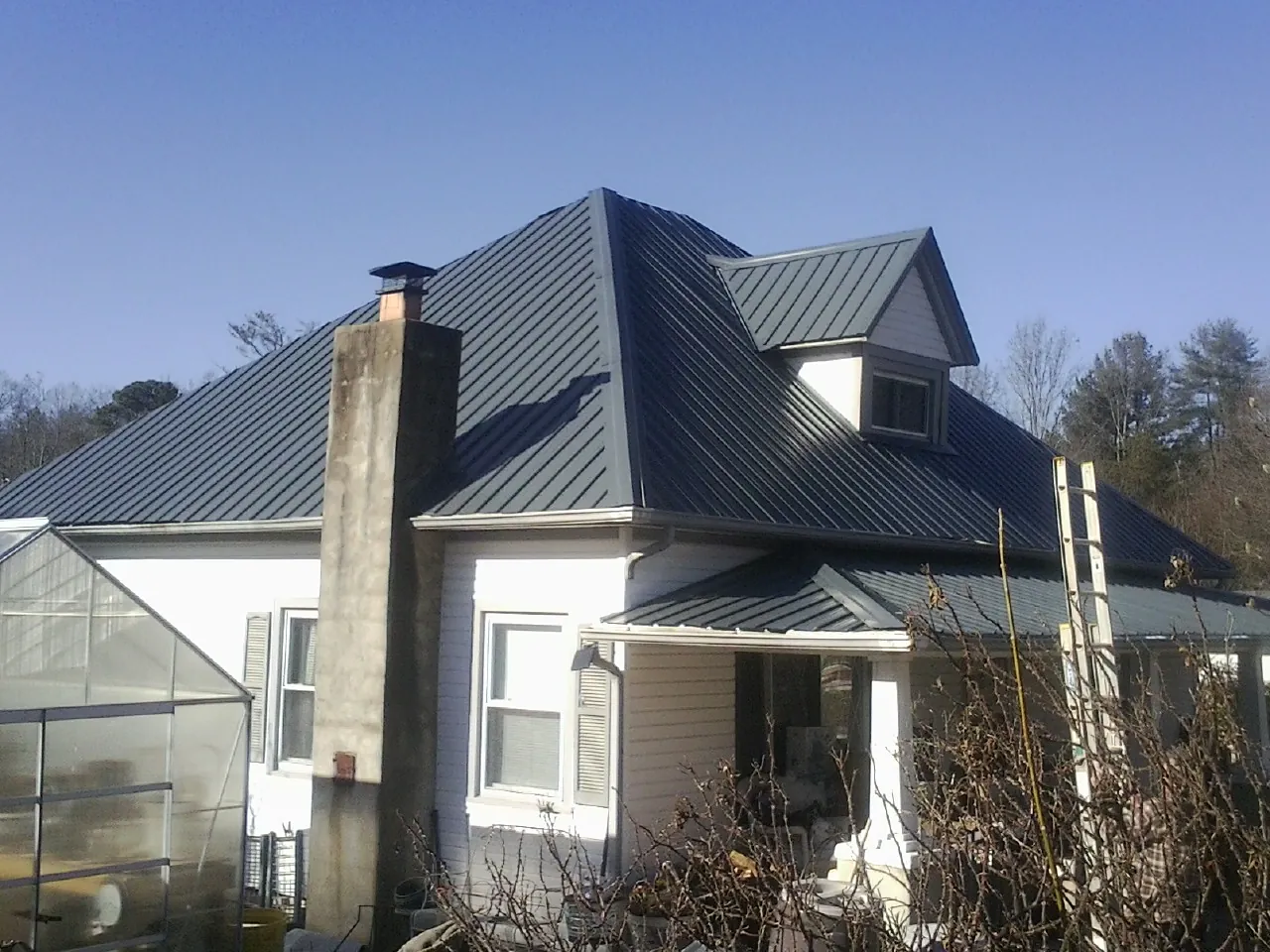 Dark blue standing seam metal roof on a white farmhouse with dormer — Slate & Tile Roof Repair by Roofing Brothers in Silverstreet