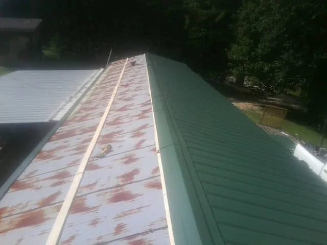 Old rusted panels beside newly installed green metal roofing — Wind Damage Roof Repair by Roofing Brothers in Silverstreet