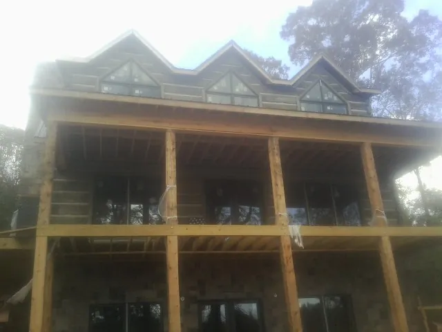 Dormers and porch framing on a large log home under construction — Roof Coating work by our crew in Silverstreet
