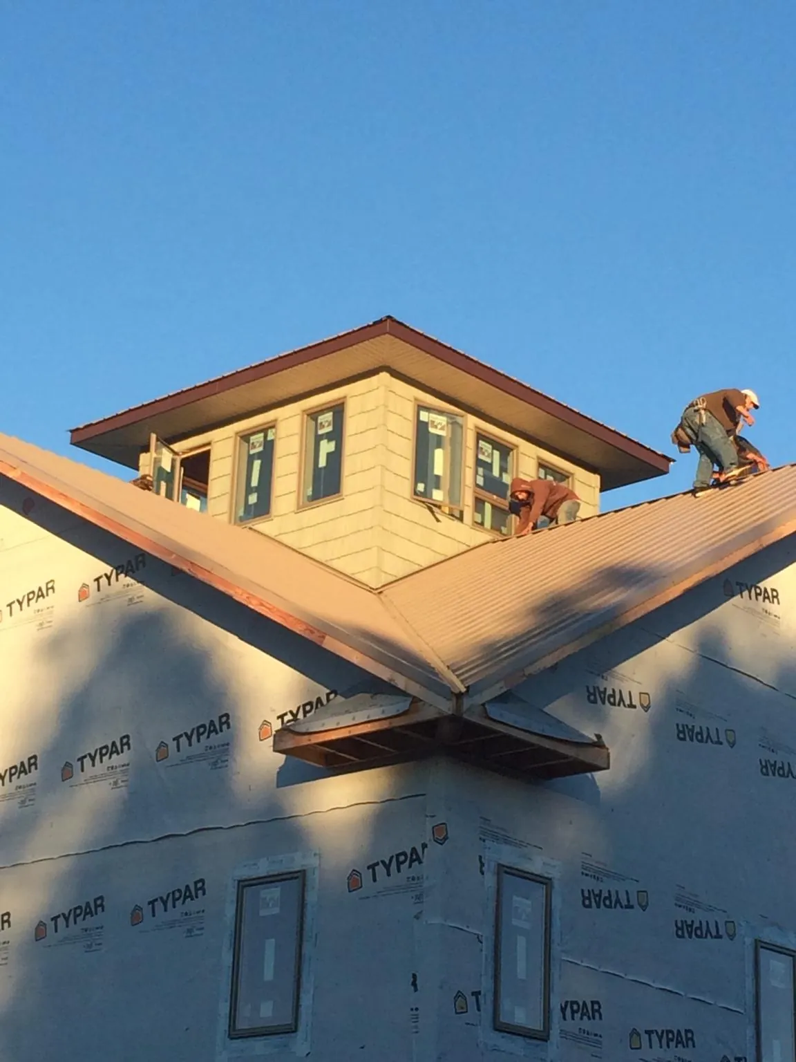 Roofers working around a rooftop cupola on a new metal roof at sunset — Roof Waterproofing in Silverstreet by Roofing Brothers